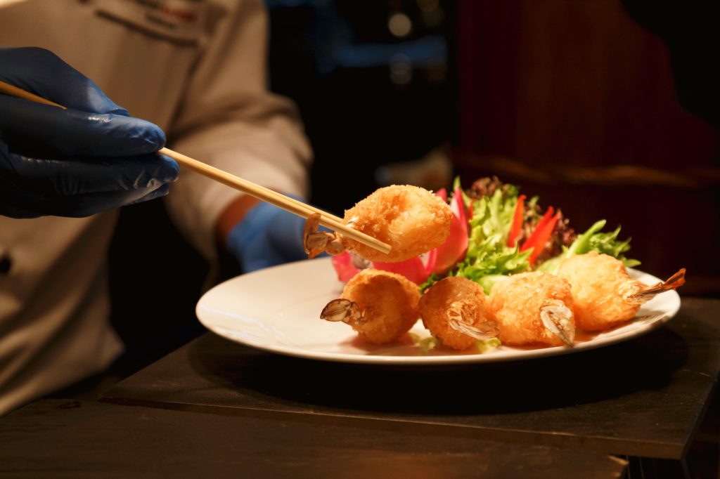 chef cooking and using chopsticks to decorating delicious dish for special dinner in restaurant.