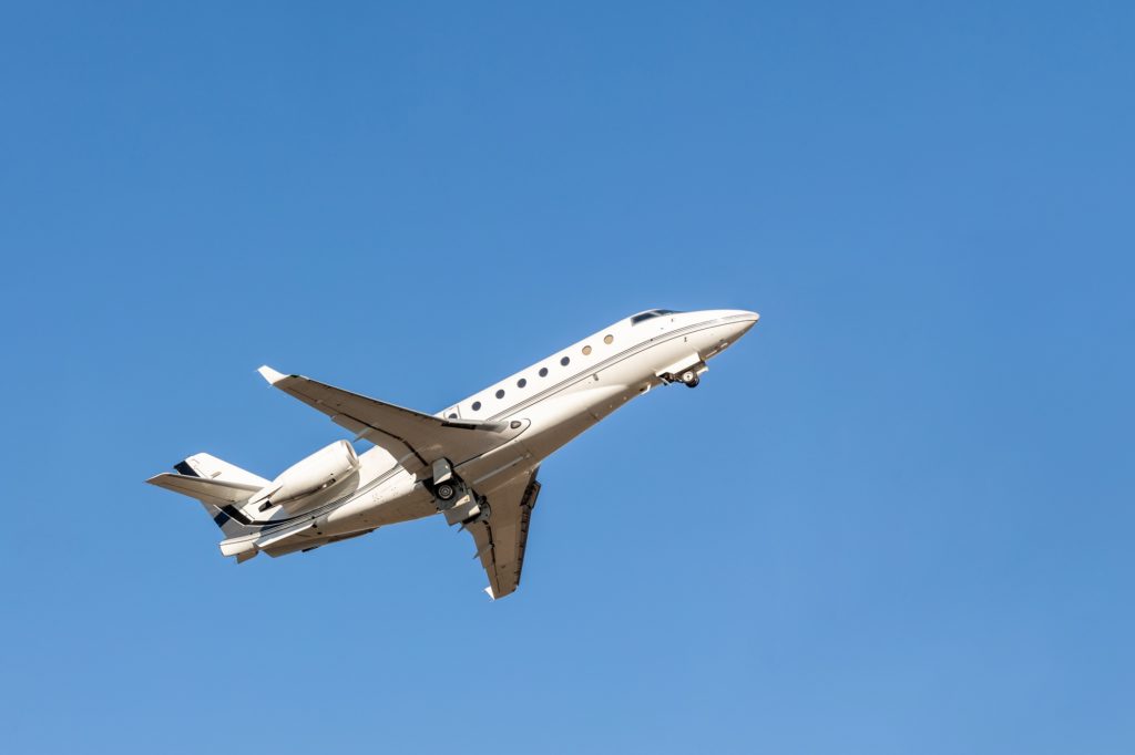 Scenic close bottom view modern luxury expensive white private jet plane dispatching from airport